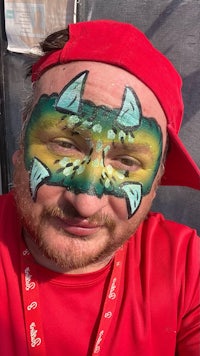 a man wearing a red hat with a dragon face painted on his face