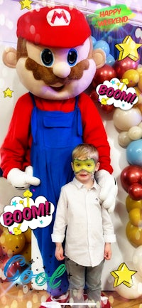 a child is posing with a mario mascot