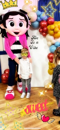 a child is standing next to a mascot dressed as a princess